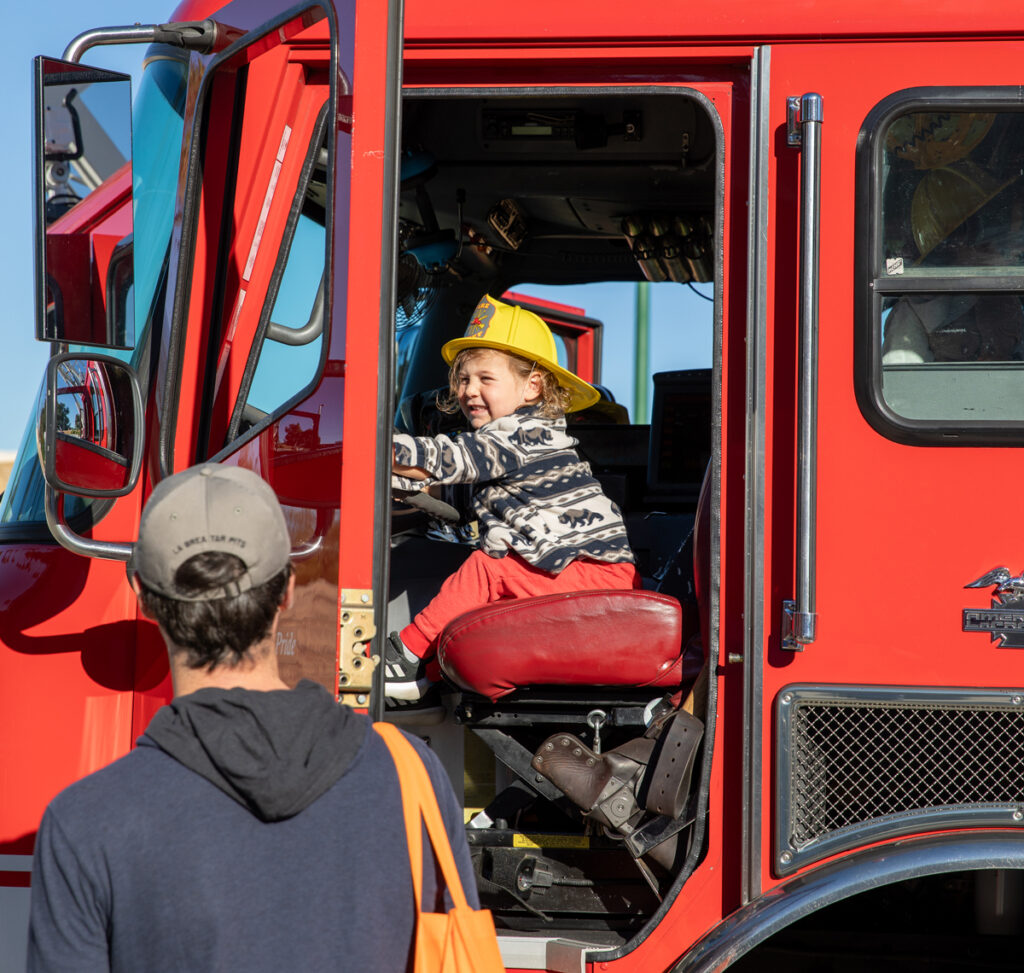 image with small child in a firetruck and yellow hat